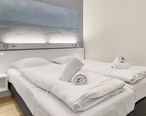 Knusse slaapkamer in Vitamaris appartement op Schiermonnikoog met kunst aan de muur.