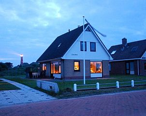 Casa Maris op Schiermonnikoog verlicht in de avondschemering met vuurtoren op de achtergrond, Waddeneilanden.