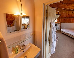 Badkamer met wastafel en spiegel in B&B De Postoari Terschelling, Hoorn, biedt comfort en stijl.