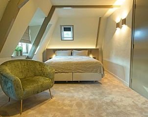 Gezellige slaapkamer in Hotel De Koegelwieck Terschelling, vakantieappartement in Hoorn met comfortabel bed en stoel.