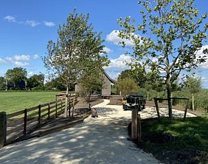 Toegangspad naar Vakantiehuis in Makkum, omgeven door groene velden en bomen, nabij het IJsselmeer in Friesland.