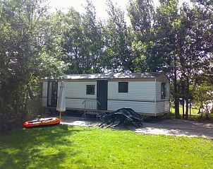 Stacaravan te midden van bomen bij Stacaravans en groepsverblijf Sotterum in Cornwerd, ideaal voor natuurliefhebbers aan het IJsselmeer.