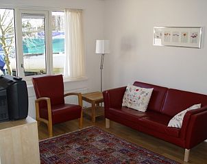 Gezellige woonkamer in Tuulikki vakantiehuis Warns, IJsselmeer, met comfortabele rode bank.