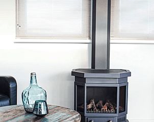 Cozy living room in Holiday Home in Oudega, Heegermeer with modern fireplace and comfortable furnishings, ideal for a relaxing stay.