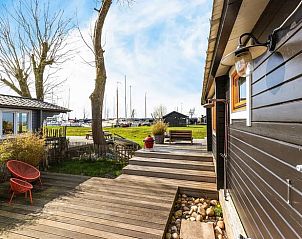 Houten veranda bij Vakantiehuis in Elahuizen met zitgelegenheid en uitzicht op de haven.