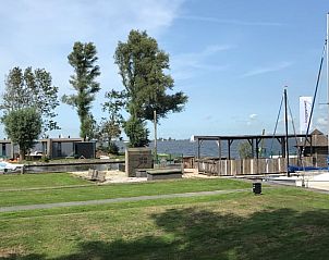 Groene tuin bij Vakantiehuis in Elahuizen met uitzicht op het meer en boten.