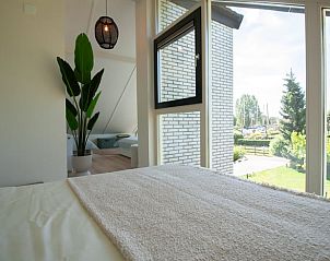 Slaapkamer met groot raam in Vakantiehuis in Gaastmeer, biedt uitzicht op de groene omgeving.