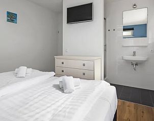 Slaapkamer met ensuite badkamer en tv in Waterpark Sneekermeer vakantiehuis, Terherne.