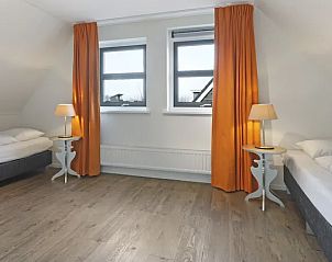 Tweede slaapkamer in Waterpark Terherne, vakantiehuis in Sneekermeer met twee eenpersoonsbedden en oranje gordijnen.