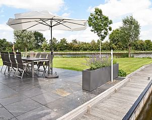 Ruim terras aan het water in Waterpark Terherne, 8-persoons waterwoning, Sneekermeer, met eetset en parasol.