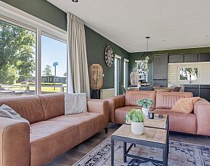 Gezellige woonkamer in Chalet het Sktsje, Offingawier, met comfortabele banken en grote ramen die uitkijken op de natuur.