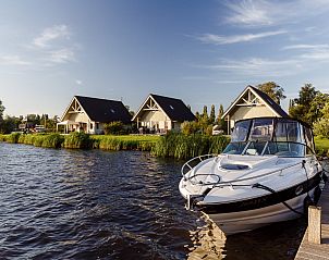 Vakantiewoning de Tjalk in Offingawier, Sneekermeer, met uitzicht op Friese meren en aangemeerde boot voor een ontspannen verblijf.
