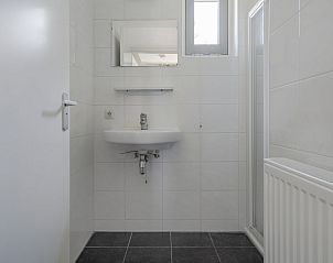 Moderne badkamer in Vakantiewoning de Tjalk, Offingawier, Sneekermeer, Friese meren, met strakke witte tegels en een stijlvolle wastafel.