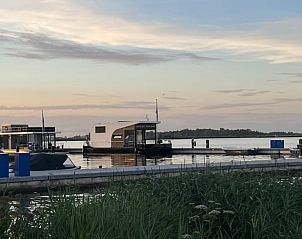 Vakantiehuis in Offingawier bij zonsondergang, drijvend op het Sneekermeer in de Friese meren.