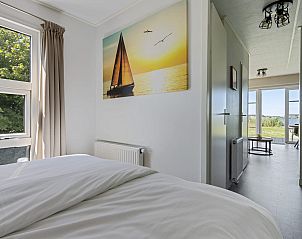 Slaapkamer in Chalet de Tjotter, Offingawier, Sneekermeer, met groot raam en serene sfeer.