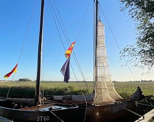 Traditionele zeilboot aangemeerd bij Vakantiehuis in Grou, Grouw, met wapperende vlaggen, nabij Pikmeer.