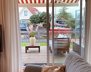 Uitzicht vanuit de woonkamer van Vakantiehuis in Grouw op het terras en het water.