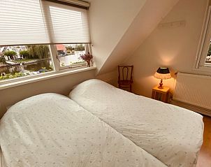 Lichte slaapkamer met twee bedden in Vakantiehuis in Grouw, uitzicht op het water.