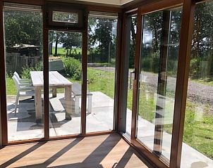 Lichte binnenruimte van Vakantiehuisje in Aldeboarn met uitzicht op het groene Pikmeer landschap.