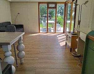 Ruime woonkamer in Vakantiehuisje in Aldeboarn met toegang tot het terras en uitzicht op de natuur.