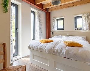 Slaapkamer in Huisje in Spier met comfortabel bed en natuurlijke lichtinval.