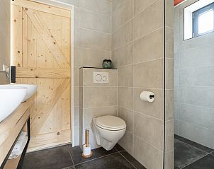 Moderne badkamer met houten deur in Huisje in Spier, Drenthe.