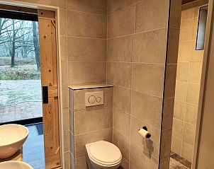 Voorzijde van DG1552 vakantiehuis in Spier, Midden Drenthe, met houten gevel en groene omgeving.