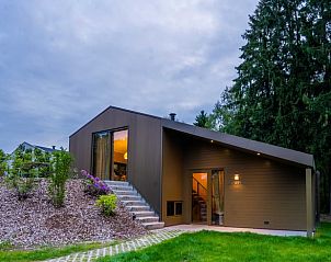 Sfeervol verlichte Vakantiehuis in Spier, Drenthe bij schemering, omgeven door groen.