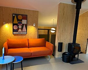 Cozy living room in Holiday Home in Spier, Midden Drenthe with orange sofa and modern wood stove for a cozy atmosphere.
