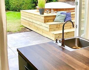 Uitzicht vanuit de keuken op de tuin en jacuzzi van Huisje in Schoonloo, Drenthe.