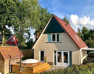 Buitenaanzicht van Huisje in Schoonloo met jacuzzi en groene omgeving in Drenthe.