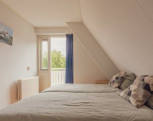 Cozy bedroom in Holiday cottage in Schoonloo, Middle Drenthe overlooking green nature through the window.