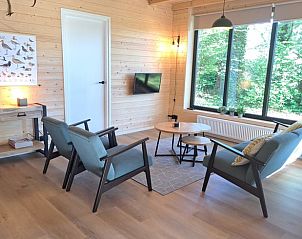 Lichte zithoek in Vakantiehuisje in Schoonloo, Drenthe met uitzicht op groen.