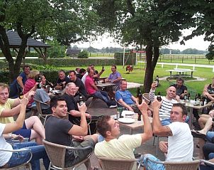 Buitenruimte met gasten genietend van het terras in Vakantiehuis in Grolloo, Midden Drenthe.