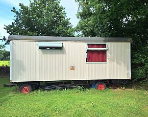 Zijaanzicht van Vakantiehuisje in Orvelte, Midden Drenthe met rode accenten en groene omgeving.