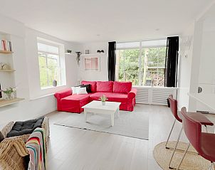 Gezellige woonkamer van Vakantiehuisje in Gasselte, Midden Drenthe met rode bank en veel lichtinval.