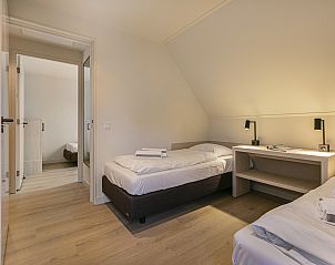 Ruime slaapkamer met twee bedden in Hof van Saksen 18-persoons boerderij, Nooitgedacht, Drenthe voor familiebijeenkomsten.