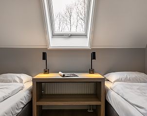 Slaapkamer met dakraam in Hof van Saksen, 12-persoons kinderboerderij in Nooitgedacht, Drenthe met natuurlijke lichtinval.