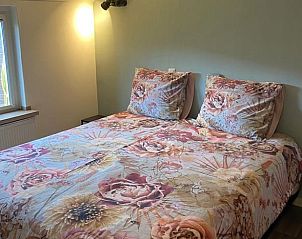 Sfeervolle slaapkamer in Vakantiehuisje in Odoorn, Midden Drenthe, met kleurrijk beddengoed en natuurlijk licht.