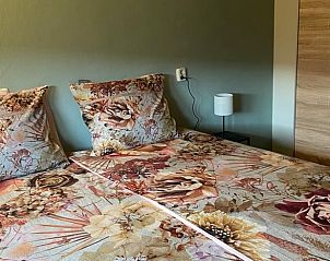 Comfortabele slaapkamer in Vakantiehuisje in Odoorn, Midden Drenthe, met bloemrijk beddengoed en nachtlampje.