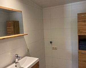 Strakke badkamer in Vakantiehuis in Odoorn, Midden Drenthe, met wastafel en opbergruimte.
