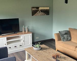 Gezellig ingerichte woonkamer in Vakantiehuis in Odoorn, Midden Drenthe, met tv en decoraties.