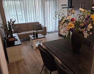 Ruime eetkamer in vakantiehuis DG2033, Odoorn, Midden Drenthe, met grote tafel en kleurrijke bloemen.