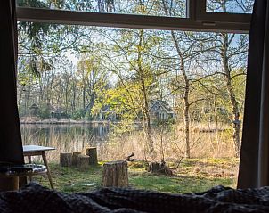 Uitzicht vanuit Huisje in Een, vakantiehuis in Noord Drenthe, met serene waterpartij en omringende bomen.