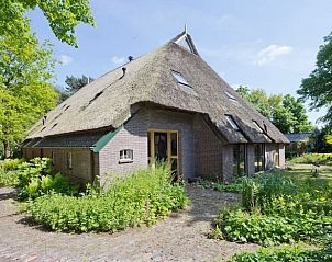 Prachtige buitenkant van Vakantiehuisje in Een, Noord Drenthe, met rieten dak en groene omgeving.