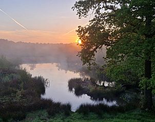 Zonsopgang bij de vijver van Huisje in Een, een vakantiehuis in Noord Drenthe, met mist en bomen.