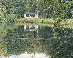 Vakantiehuis Huisje in Een, Drenthe weerspiegeld in een rustige vijver.
