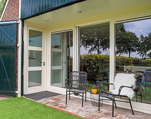 Ruim terras bij Vakantiehuis in Een, Drenthe, met comfortabele stoelen en uitzicht op de groene omgeving.