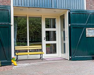 Stijlvolle ingang van Vakantiehuisje in Een, Drenthe, met groene deuren en kleurrijke bloemen.