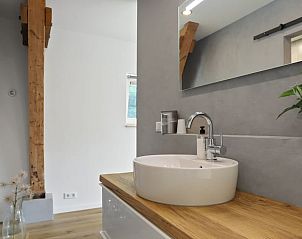 Elegante wastafel met houten blad in Vakantiehuisje in Een, Drenthe, met moderne kraan en spiegel.